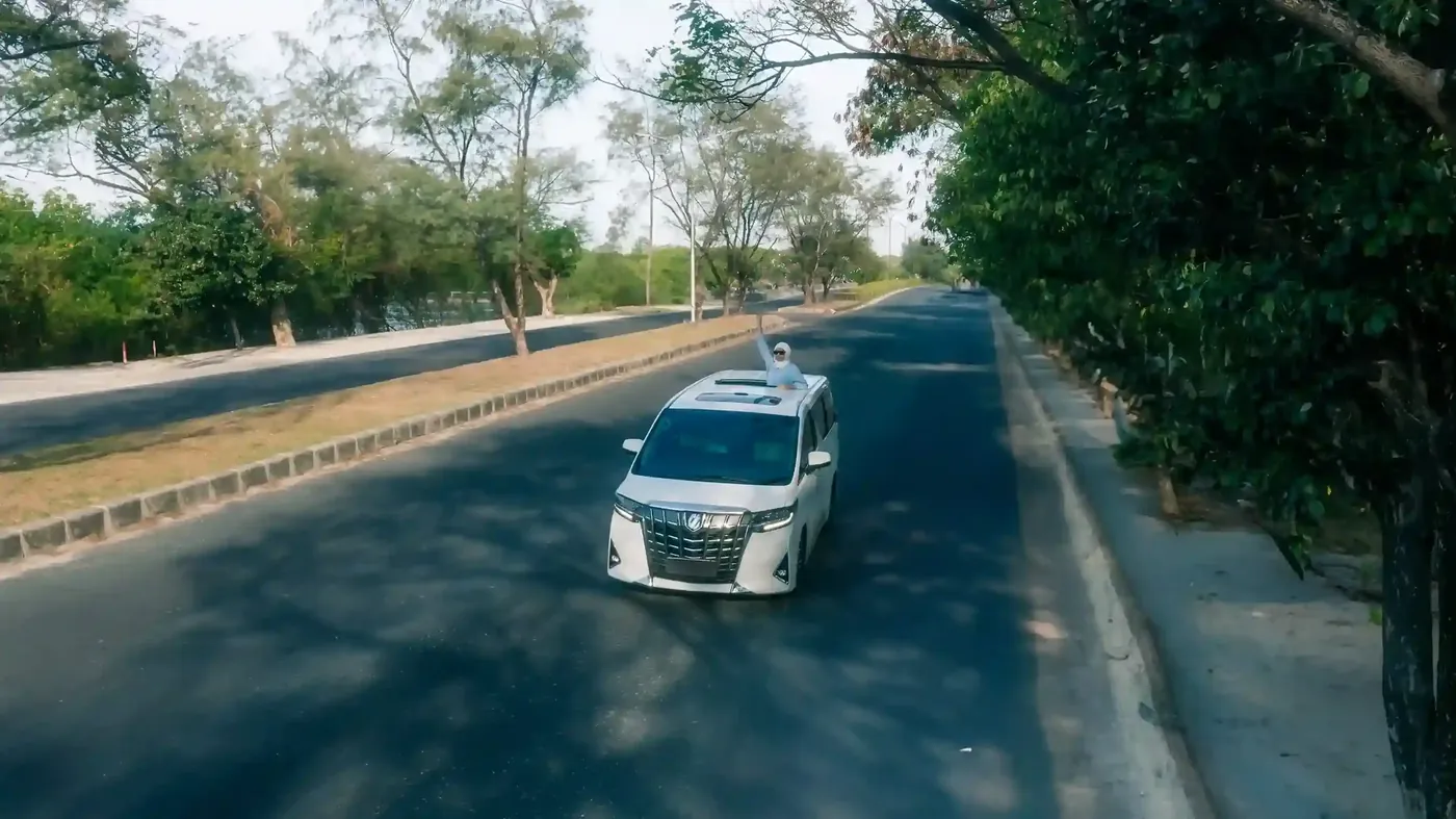 An aerial view of a white Alphard on a quiet Bali road