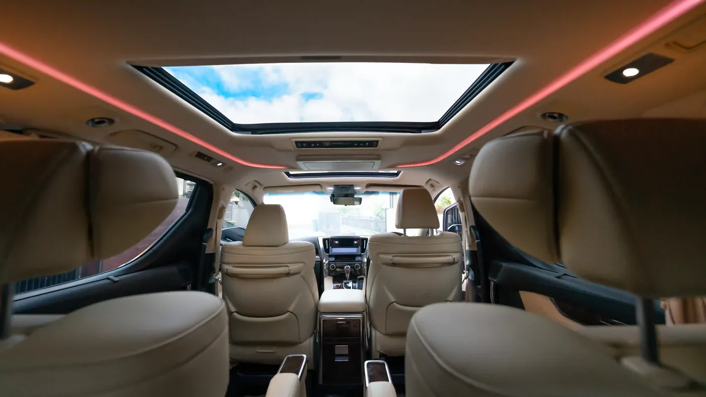 The rear cabin of an Alphard with sunroof and ambient lighting