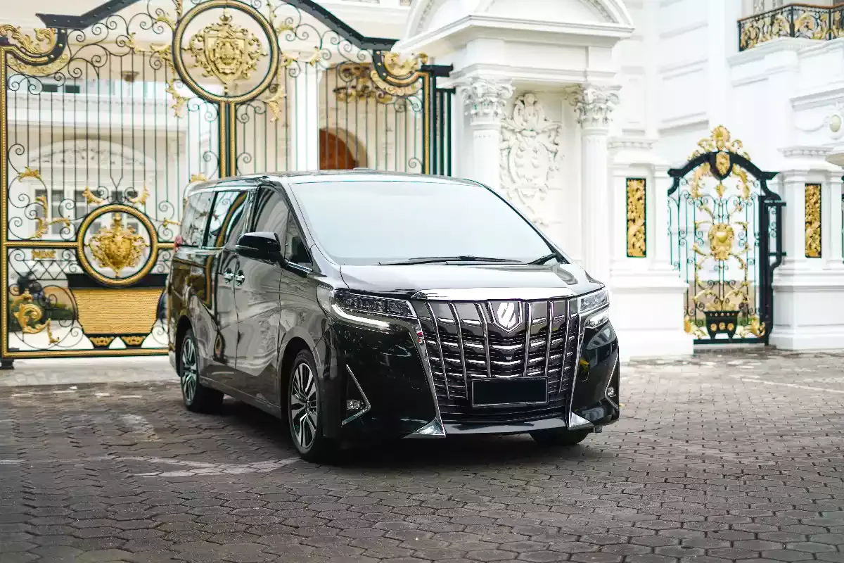 A black Toyota Alphard parked at a gated entrance