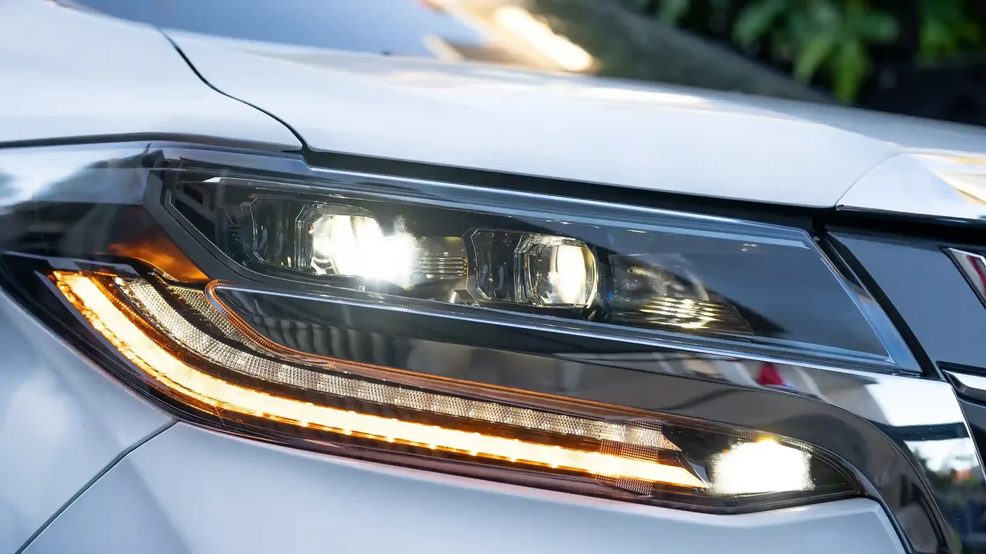 The headlight of a white Toyota Alphard