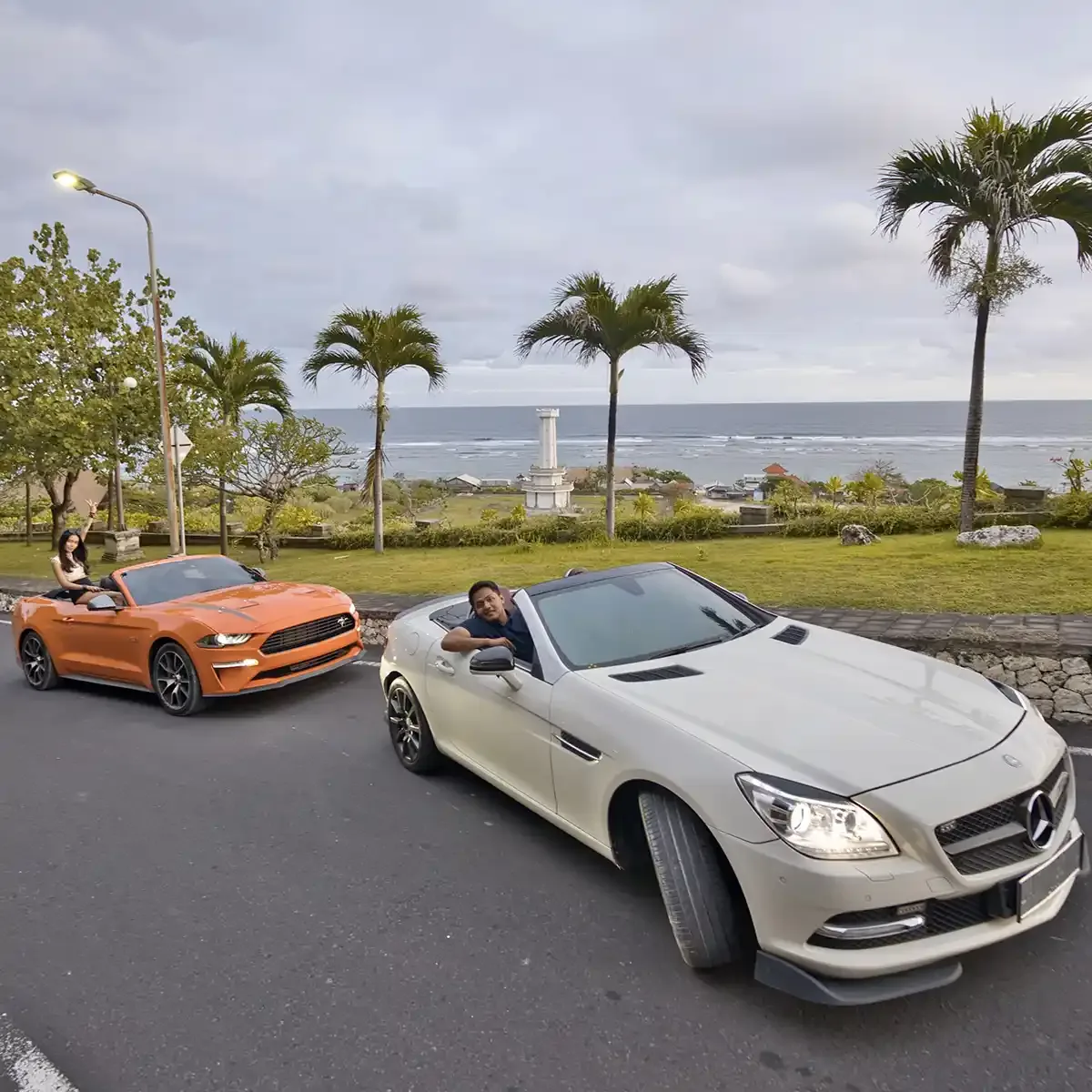 Two convertibles parked on a seaside road in Bali