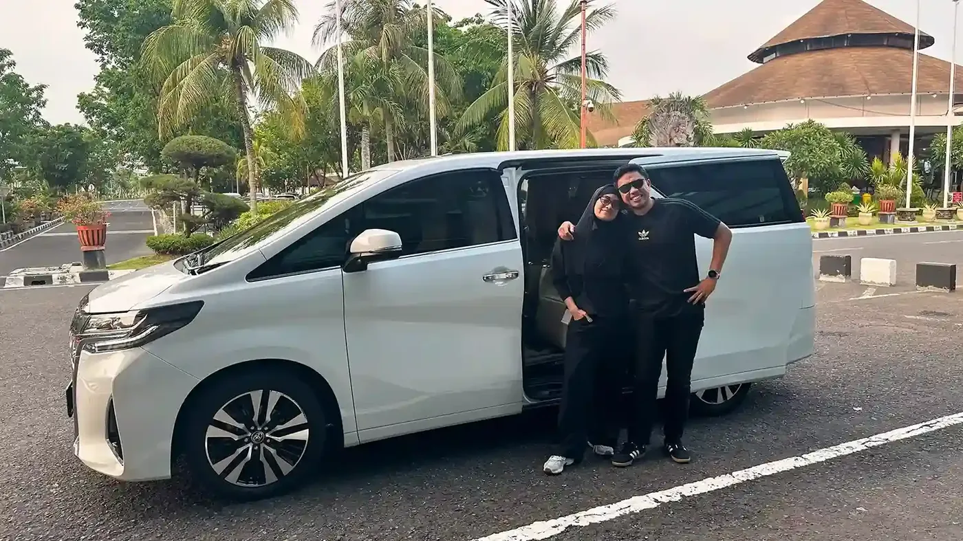 Guests beside a white Toyota Alphard on the Ngurah Rai airport forecourt